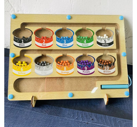 Color sorting toy with labeled bins on a wooden board